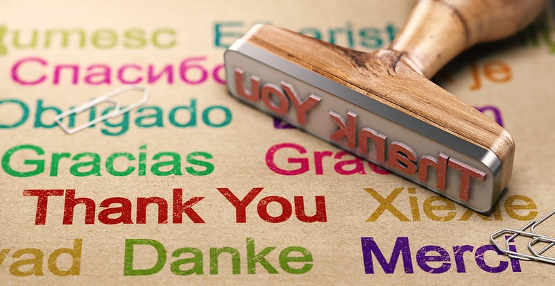 Een meertalige postzegel met de woorden 'dank u' erop geschreven.
