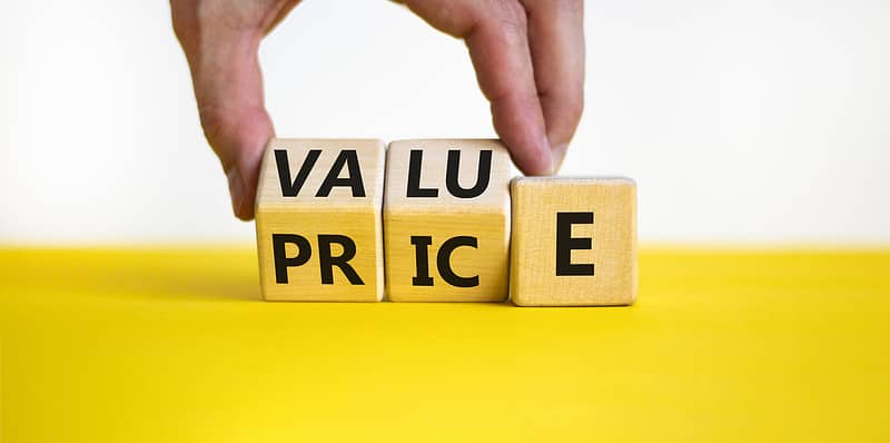 A person holding wooden blocks at home with the word value price on them.